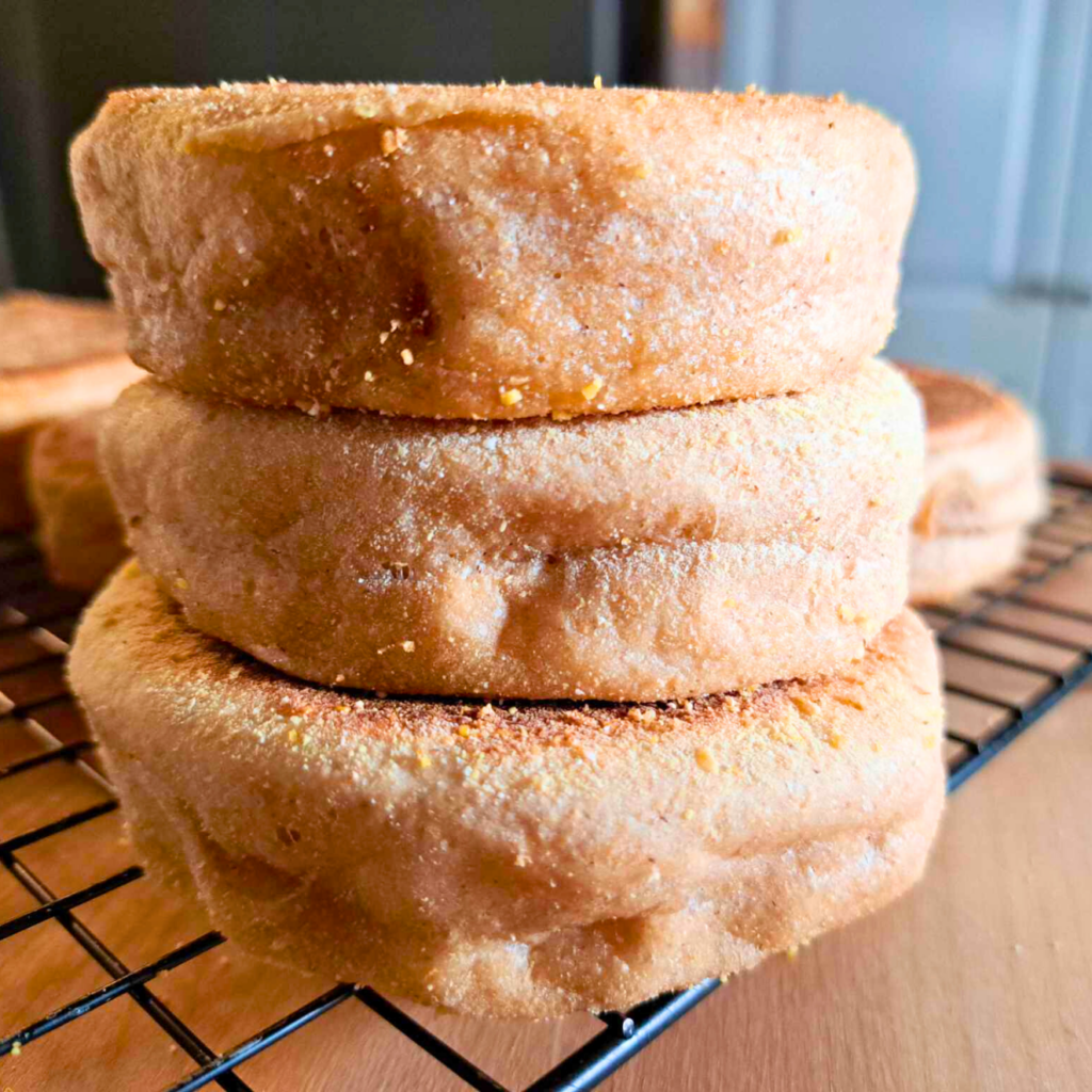 homemade English muffins made with fresh milled flour stacked on a cooling rack.