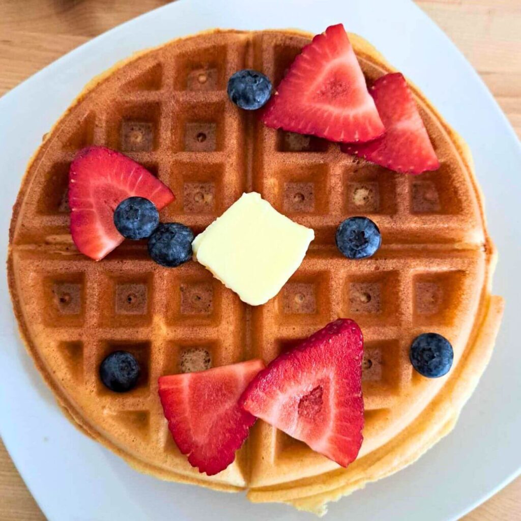 circle round belgian waffle made with fresh milled soft white wheat flour topped with blueberries and strawberries