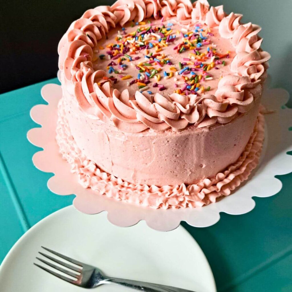 fresh milled flour strawberry cake with strawberry buttercream on a cake stand