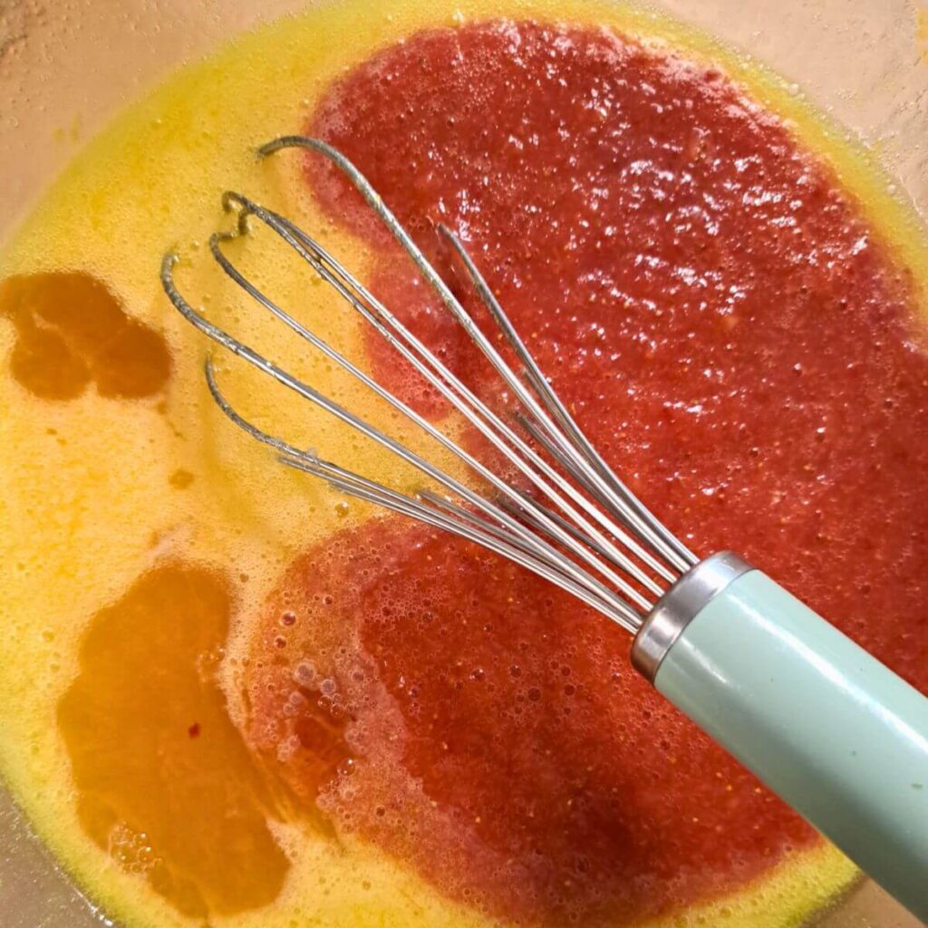 Melted butter, sugar, eggs, strawberry puree, vanilla, and strawberry extract together in bowl for strawberry cake